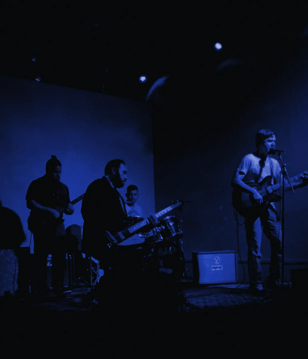 In_Motion on stage: four players under a few lights, the room falling to black